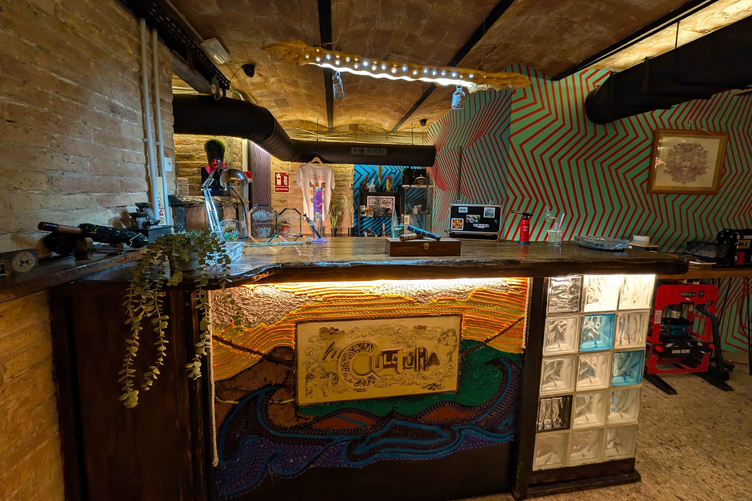 Espace bar du club social La Cultura avec comptoir artistique et mur dynamique à Barcelone
